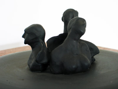 A detail of the Anguish sculpture showing only the three figures, painted black.