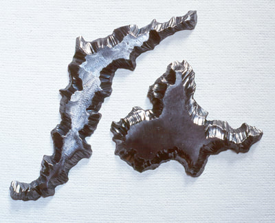 An abstract steel wall sculpture cut in two ragged shapes that look like islands. 