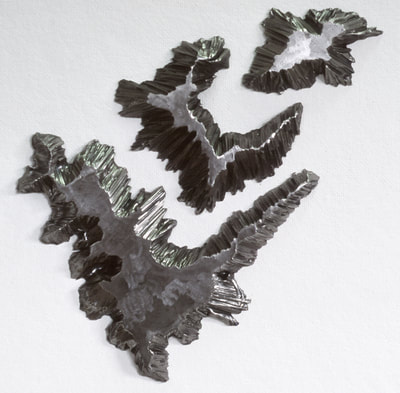 A three section Archipelago Element with beautifully raggedly cut edges as though they had eroded. This steel island sits on a seascape of wall. 