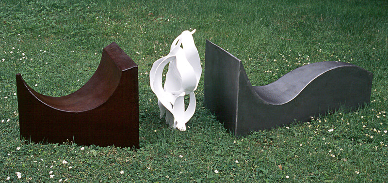 On the lawn at the Moses-Kent House Museum, three abstract, curving steel elements - one dark rust colored, one white, and one grey.