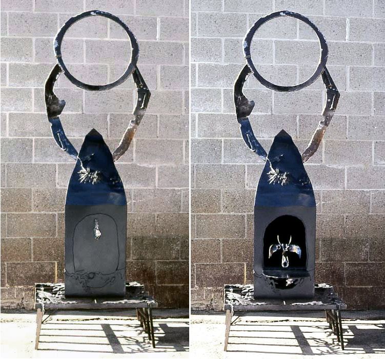 Black sculpture with an enso-like circle on top held up by two arms. An open door reveals a face-like shape. 