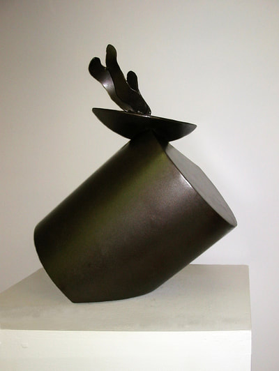 An abstract steel sculpture of three shapes balanced on one another. 
